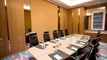 A conference room with a long table, black chairs, and a patterned carpet.