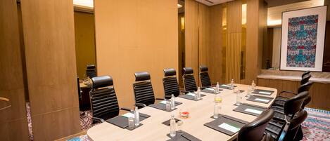A conference room with a long table, black chairs, and a patterned carpet.