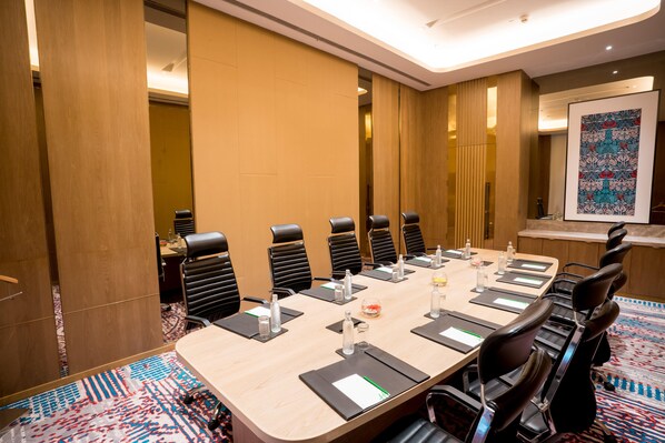 A conference room with a long table, black chairs, and a patterned carpet. - Holiday Inn Lucknow Airport (Lucknow)