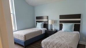 A bedroom with two beds, each with a headboard and bedside tables.