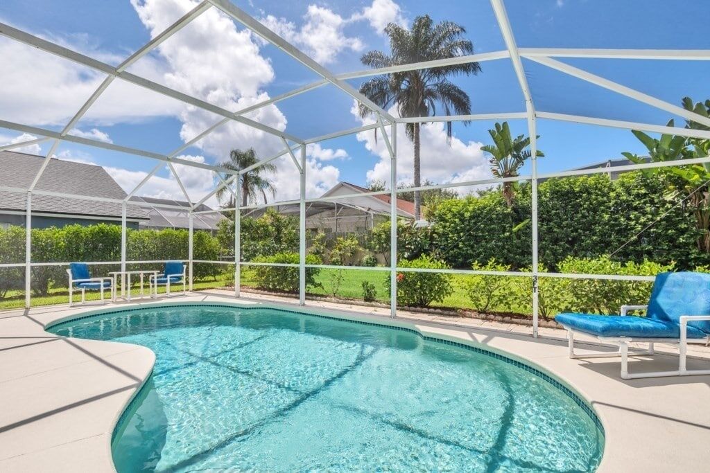 Una piscina con techo blanco, rodeada de follaje y un cielo despejado.