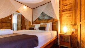 A wooden room with a bed, a nightstand, and a wall-mounted lamp.