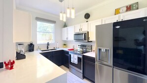 A modern kitchen with stainless steel appliances, white cabinetry, and pendant lighting. - Modern 4br Home In Regal Palms Resort Near Disney 4 Bedroom Townhouse (Davenport)