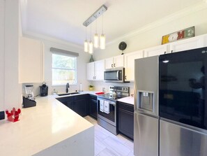 A modern kitchen with stainless steel appliances, white cabinetry, and pendant lighting. - Modern 4br Home In Regal Palms Resort Near Disney 4 Bedroom Townhouse (Davenport)