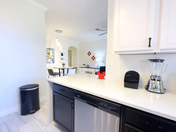 A modern kitchen with white cabinets, a dishwasher, a blender, and a trash can. - Modern 4br Home In Regal Palms Resort Near Disney 4 Bedroom Townhouse (Davenport)