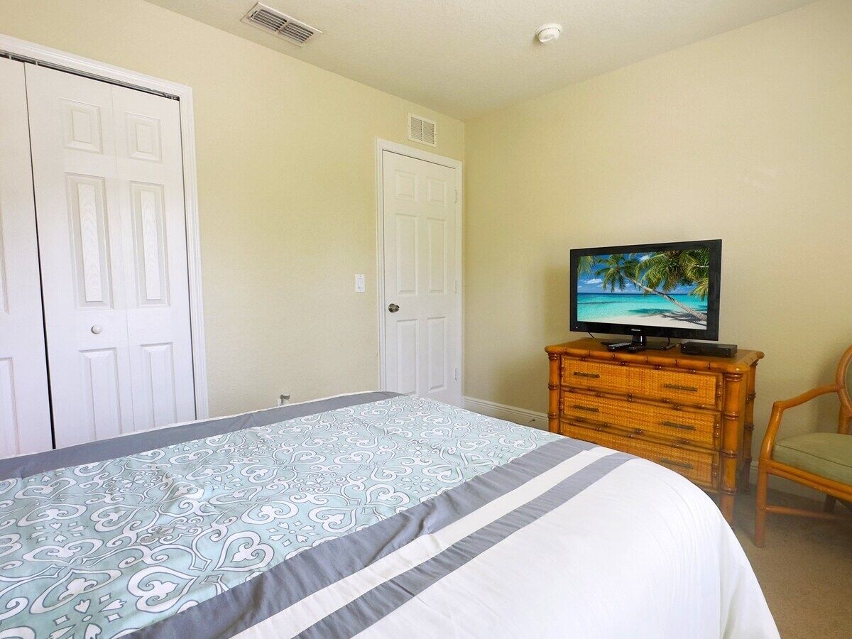 Une chambre à coucher avec un lit, un téléviseur posé sur une commode et une chaise.