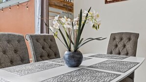 A dining table with a vase of white flowers, grey upholstered chairs, and a decorative table runner. - 4bd Villa Near Epic Universe And Disney With Private Pool 4 Bedroom Townhouse (Kissimmee)