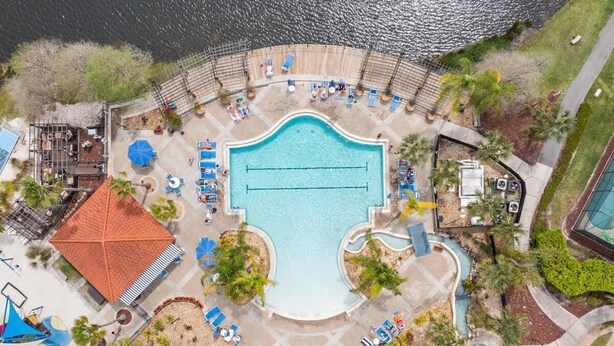 An aerial view of a resort with a central swimming pool, sun loungers, and a small boat dock. - 4bd Villa Near Epic Universe And Disney With Private Pool 4 Bedroom Townhouse (Kissimmee)