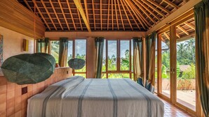 A bedroom with a large bed, wooden ceiling beams, and a view of greenery outside. - Moon Gang Ubud (Ubud)