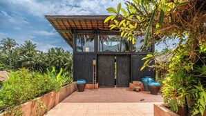 A modern building with large glass windows, a wooden deck, and surrounding lush greenery. - Moon Gang Ubud (Ubud)