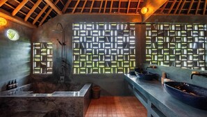 A modern bathroom with a large bathtub, a shower, and a sink with a blue basin. - Moon Gang Ubud (Ubud)