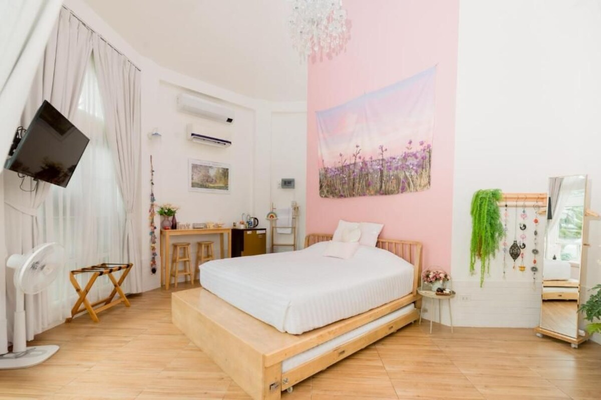 Ein Schlafzimmer mit einem Bett, einem Schreibtisch, einem Stuhl, einem Fernseher und einer Wand mit einem Gemälde.