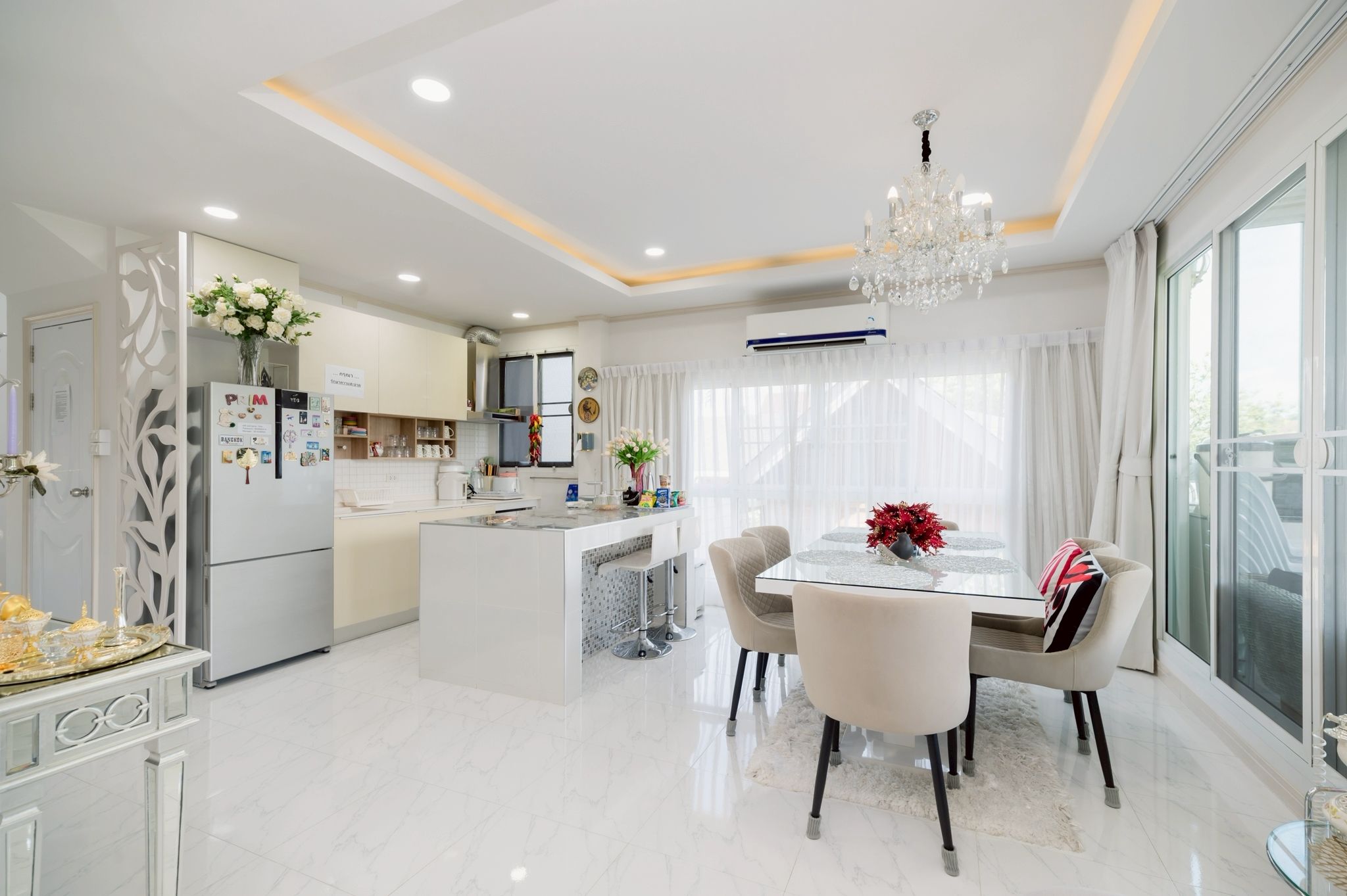 A modern kitchen with a dining area, featuring a central island, white cabinetry, and a chandelier.