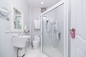 Ein modernes Badezimmer mit Waschbecken, Toilette und Dusche, alles in Weiß.