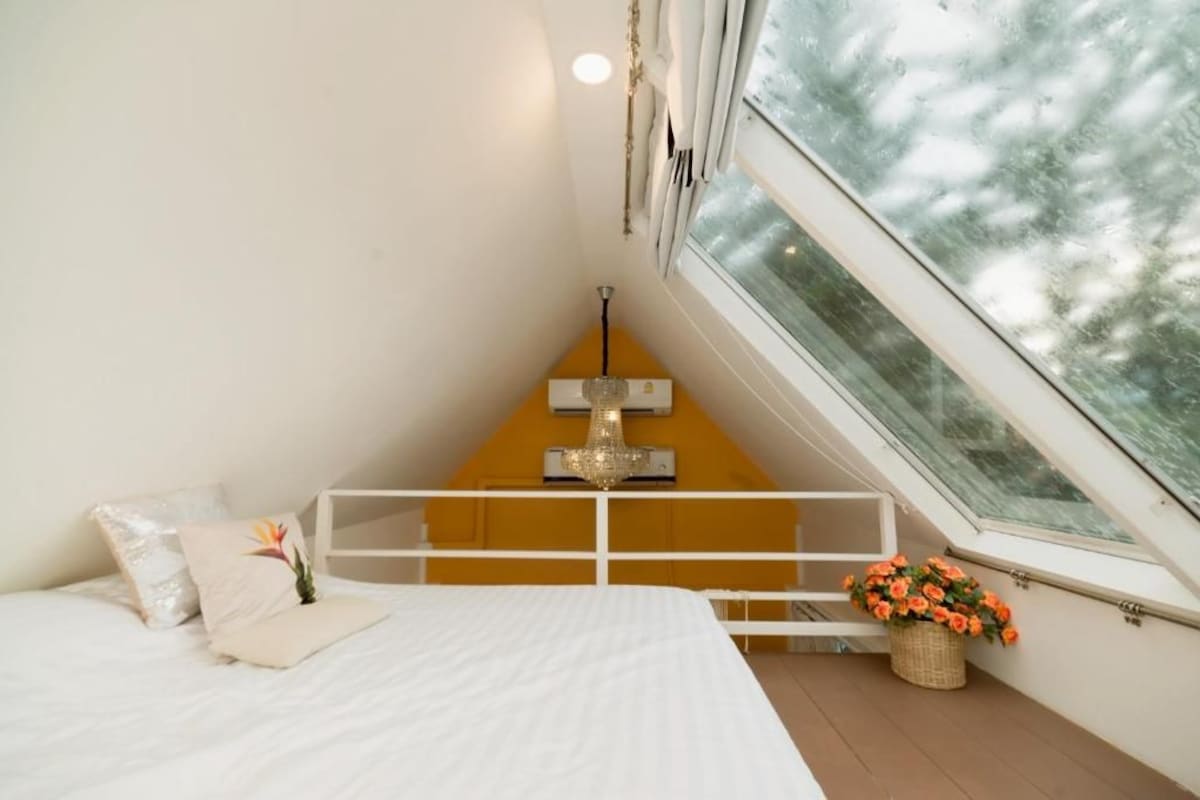 Ein Schlafzimmer mit Bett, einer Kandelaber, einem Fenster und einem Balkon mit Blumen.