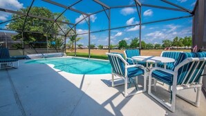 A covered outdoor area with a pool, lounge chairs, and a table. - Villa Near Disney 4 Bd 3 Bt With Private Pool Quiet Comminuty 4 Bedroom Home (Davenport)