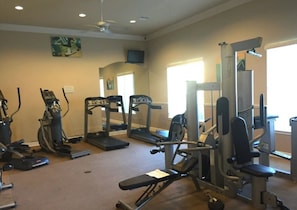 Ein Fitnessstudio mit verschiedenen Trainingsgeräten, darunter Laufbänder, Crosstrainer und Kraftgeräte.