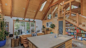 A spacious kitchen with a large island, wooden beams, and a staircase leading to an upper level.