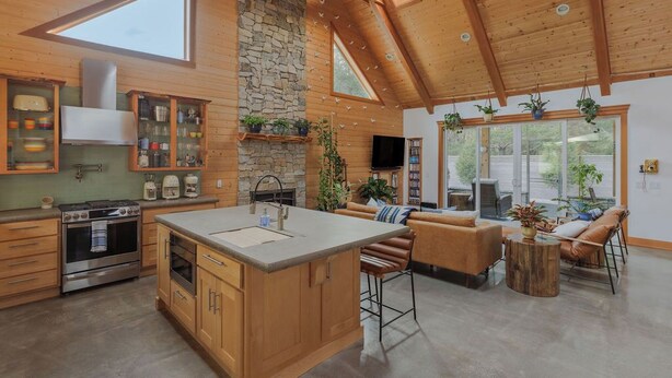 A spacious kitchen with wooden cabinets, a large island, and a stone fireplace.