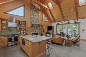 Una cocina amplia con armarios de madera, una isla grande y una chimenea de piedra.