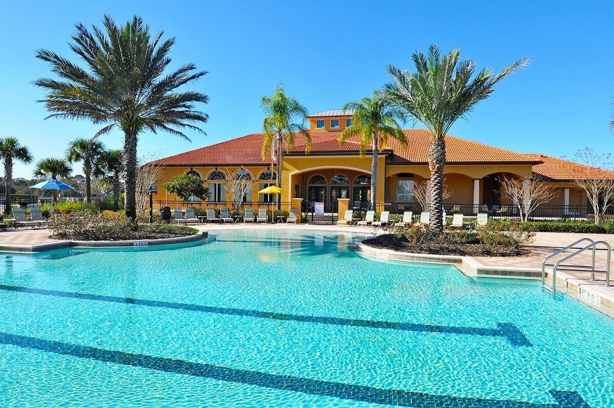 Un hotel con piscina, palmeras y techo de tejas rojas.
