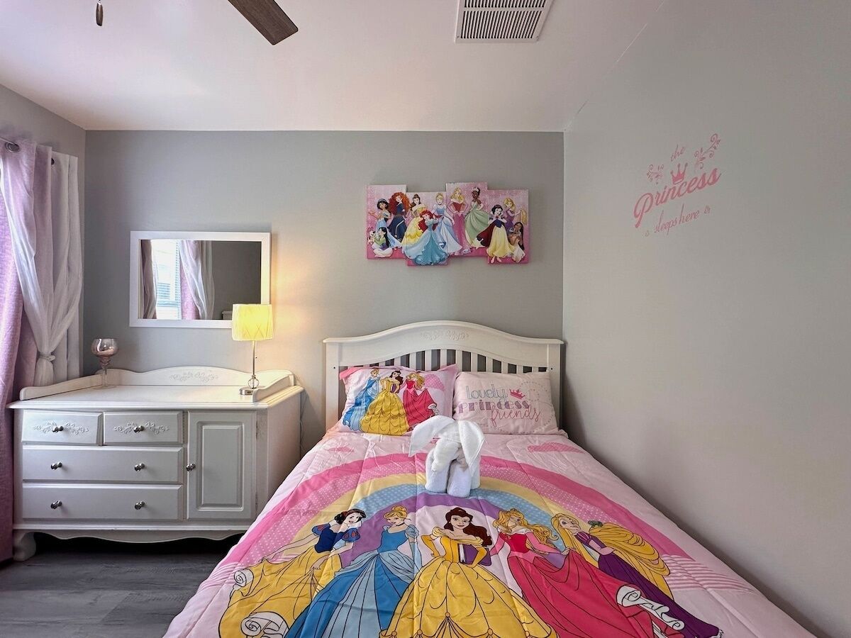 A bedroom with a bed, a dresser, a mirror, and wall decorations.