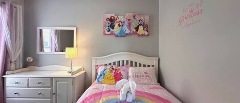 A bedroom with a bed, a dresser, a mirror, and wall decorations.