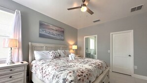 A bedroom with a bed, nightstands, a ceiling fan, a painting, and a door. - Luxury Villa Near Disney 6 Bd Home With Private Pool And Resort 6 Bedroom Home (Davenport)