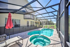 A covered outdoor swimming pool with lounge chairs and a red umbrella. - Near Disney Amazing 5 Bd Home - Private Pool 5 Bedroom Home (Davenport)
