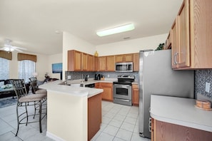 A modern kitchen with wooden cabinets, stainless steel appliances, and a central island. - Near Disney Amazing 5 Bd Home - Private Pool 5 Bedroom Home (Davenport)