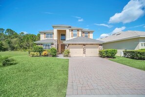 A two-story house with a garage, a paved driveway, and a well-maintained lawn. - Near Disney Amazing 5 Bd Home - Private Pool 5 Bedroom Home (Davenport)