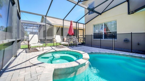 Ein Schwimmbecken mit Whirlpool, umgeben von Liegestühlen und einer überdachten Terrasse.