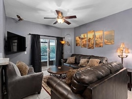 A living room with a leather sofa, a coffee table, a flat-screen TV, and artwork on the wall.