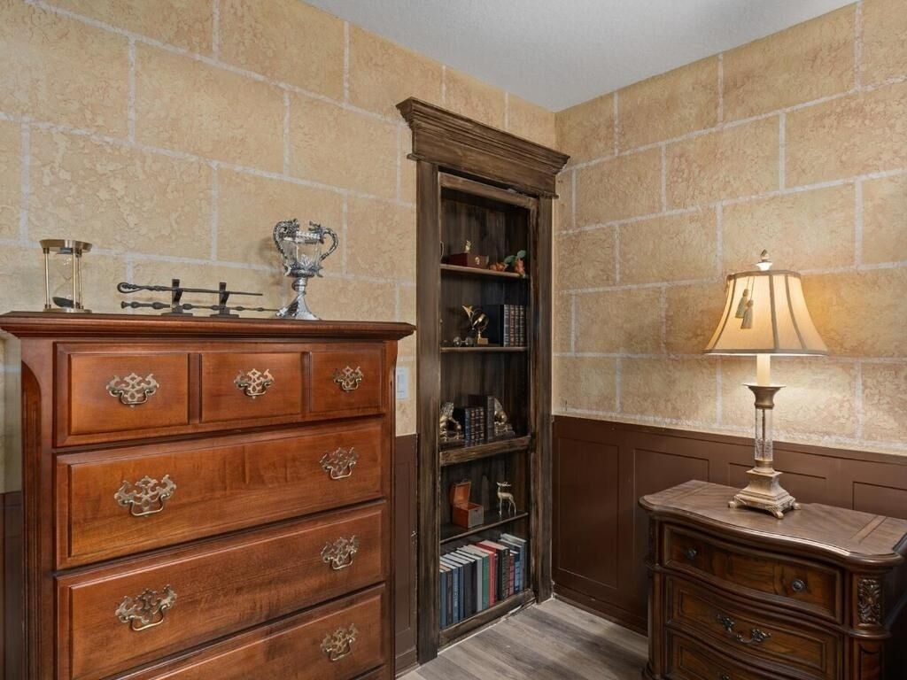 A corner room with a wooden dresser, a tall bookcase, and a lamp.
