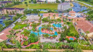 A resort with multiple swimming pools, palm trees, and a central building with a red roof. - Fully Themed Harry Potter Getaway Close Disney 3 Bedroom Townhouse (Davenport)