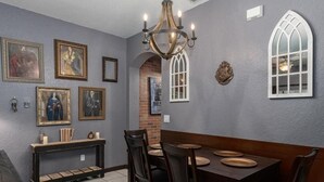 A dining area with a long table, chairs, a chandelier, framed artwork, and a decorative window. - Fully Themed Harry Potter Getaway Close Disney 3 Bedroom Townhouse (Davenport)
