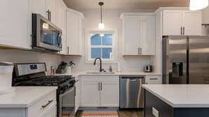 Een moderne keuken met witte kasten, roestvrijstalen apparatuur en een centraal eiland.