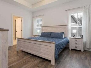 A bedroom with a wooden bed, a nightstand, a dresser, and a window with curtains. - Land of the Pines | Single-Level Blue Ridge Retreat Near Asheville + Biltmore (Fairview)