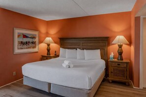 A hotel room with a large bed, two bedside tables, a headboard, and a painting on the wall. - The Coastal Retreat | Three F (Myrtle Beach)
