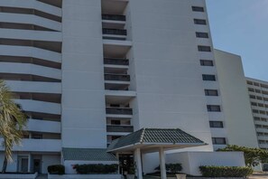 A multi-story building with balconies, a covered entrance, and a clear sky. - The Coastal Retreat | Three F (Myrtle Beach)