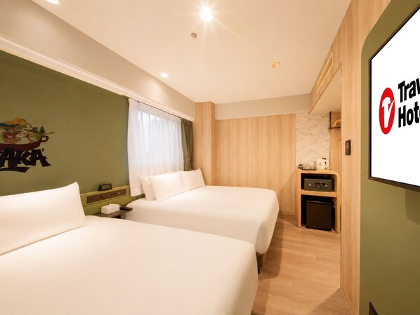 Habitación de hotel con dos camas, un escritorio pequeño, un espejo y una televisión de montaje en pared.