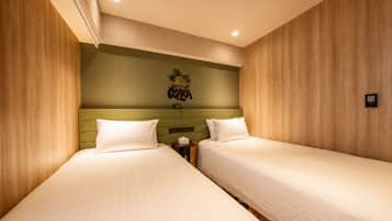 Una habitación de hotel con dos camas individuales, un cabecero verde y una obra de arte colgada en la pared.