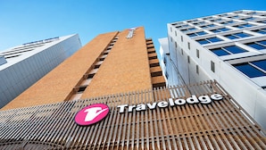 Um hotel Travelodge com um logotipo 'T' em destaque, fachada de tijolos e design moderno.