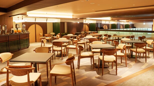 Um restaurante espaçoso com várias mesas e cadeiras, um balcão com bebidas e um design de interiores moderno.