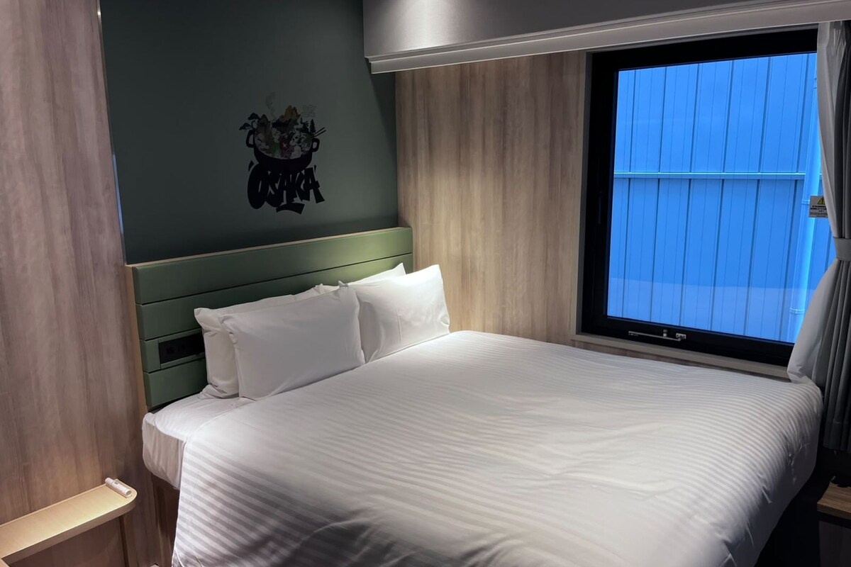 Una habitación de hotel con una cama grande, un cabecero, una ventana con cortinas y una decoración en la pared.