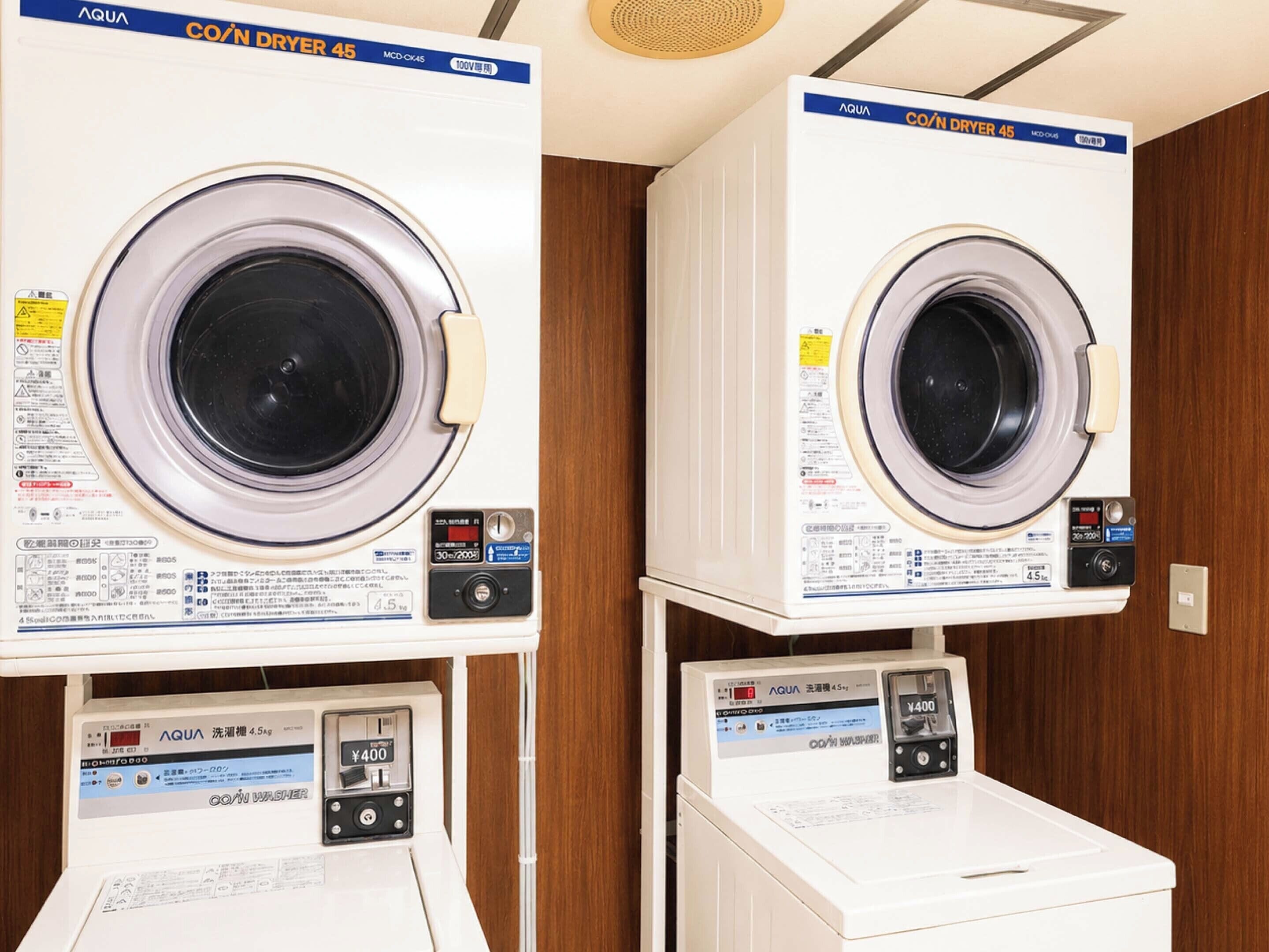Two identical front-loading washing machines with control panels, placed on wooden cabinets.