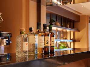 A bar area with various bottles of alcohol, including whiskey and sake, on a reflective surface. - Travelodge Osaka Shinsaibashi (Osaka)