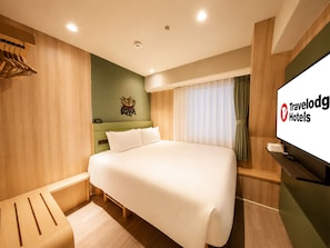 A hotel room with a large bed, a wooden headboard, a flat-screen TV, and a wall-mounted towel rack. - Travelodge Osaka Shinsaibashi (Osaka)