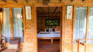Una cabaña de madera con una cama, un banco y el número '09' en la pared.