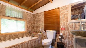 Un baño con pared de piedra, una bañera, un inodoro y un lavamanos.